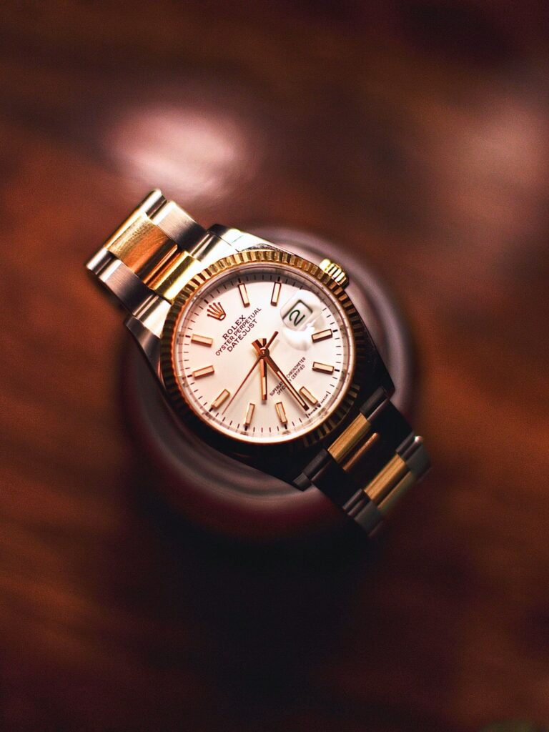 Overhead view of a rolex watch with white dial against a hardwood background.
